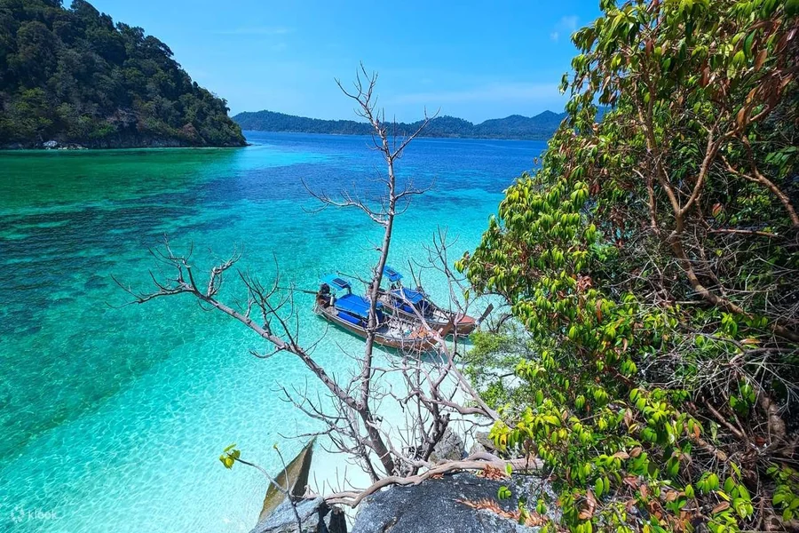 Pristine white sand beach at Koh Lipe with crystal-clear turquoise waters and traditional longtail boats